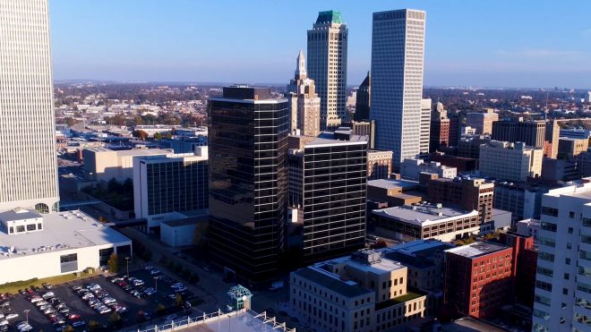 Aerial view of the Tulsa, Oklahoma city skyline featuring prominent glass office towers and surrounding buildings.