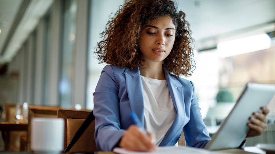 Photo of a businesswoman holding a tablet and reviewing documents at a table